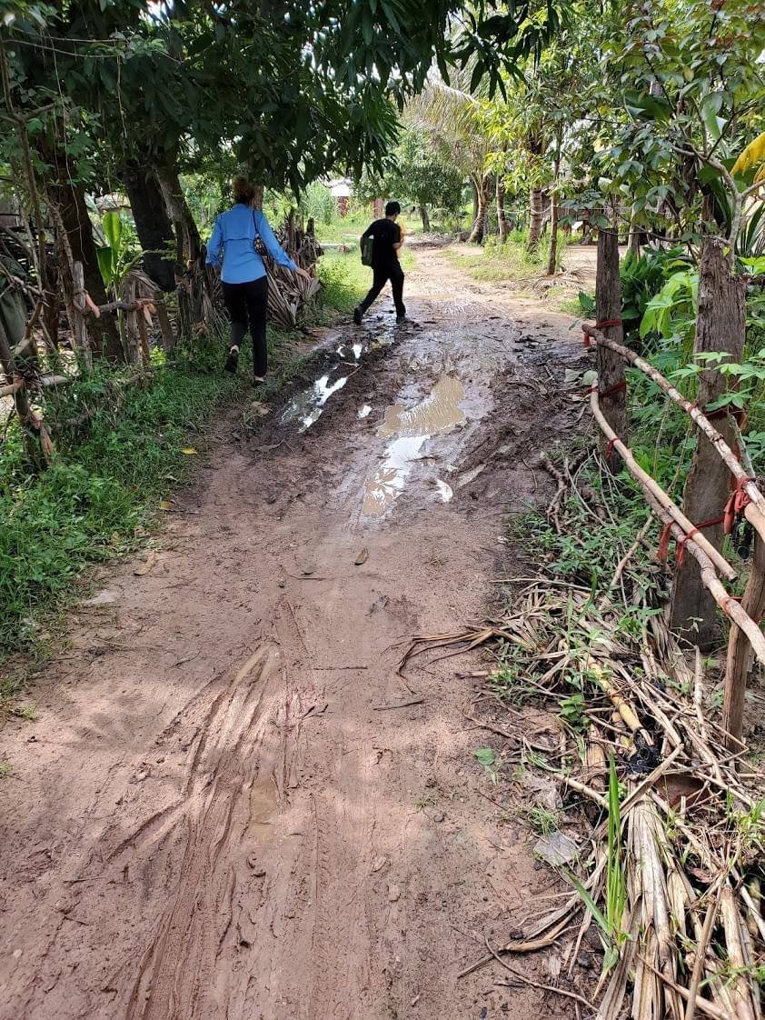 Trina & Bol navigating one of many muddy paths during some long hikes to visit remote Cambodian "well" families Trina & Bol navigating one of many muddy paths during some long hikes to visit remote Cambodian "well" families